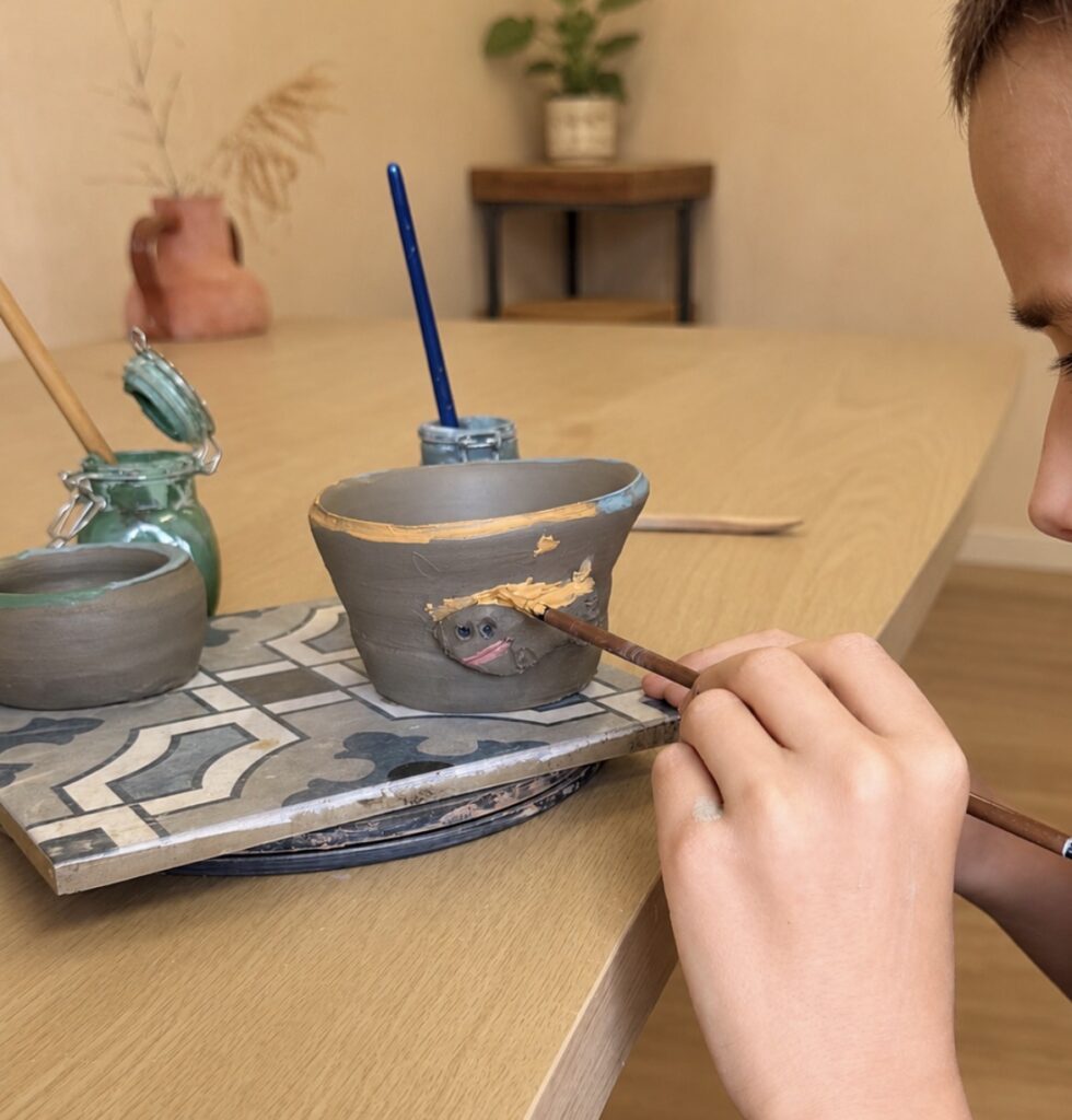 Child painting handmade pottery